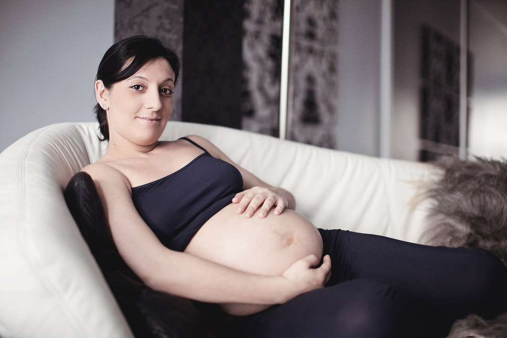Pregnant woman reclining on a couch. Photo by John Hope. Article: Why bother with a postnatal doula? Written by Kelly Harper, Elemental Beginnings Adelaide