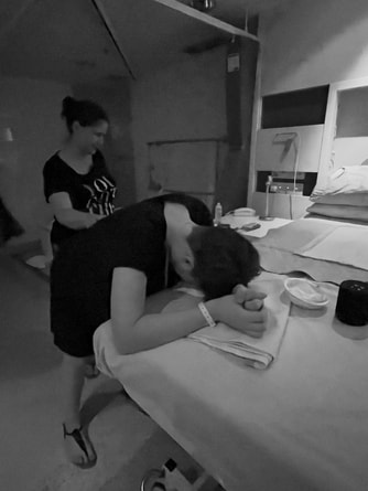 Image is of a labouring woman standing and leaning on a hospital bed, while her doula from Adelaide provides physical comfort techniques during her hypnobirth at Flinders Medical Centre