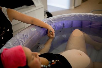 Adelaide doula Kelly Harper providing physical support to a woman labouring in a birth pool at home