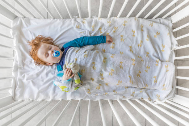 Young boy sleeping safely in cot with comfort items | Gentle Sleep Consultant Adelaide | Kelly Harper
